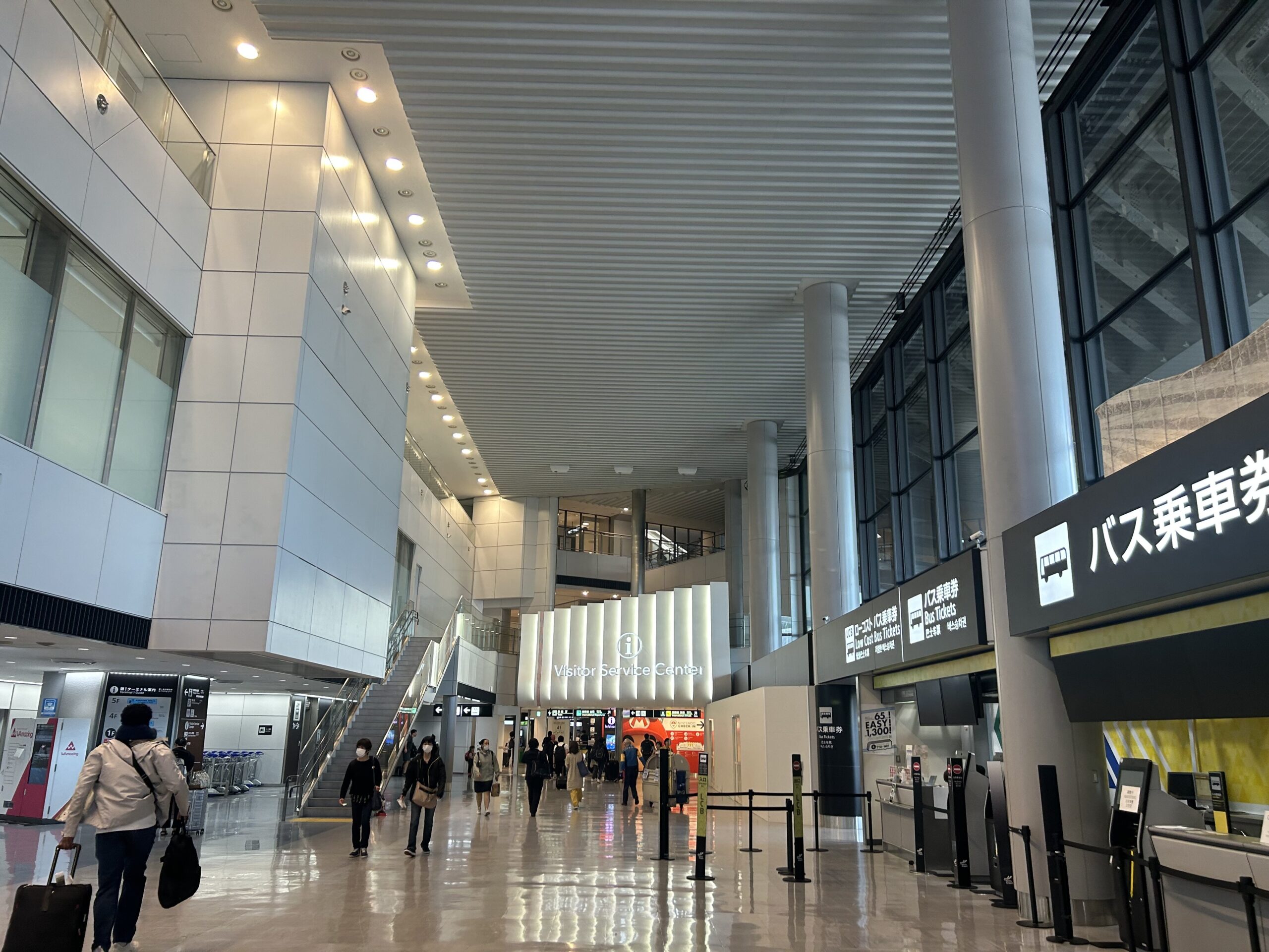 Travelers walking through the bright arrivals hall at Narita Airport Terminal One