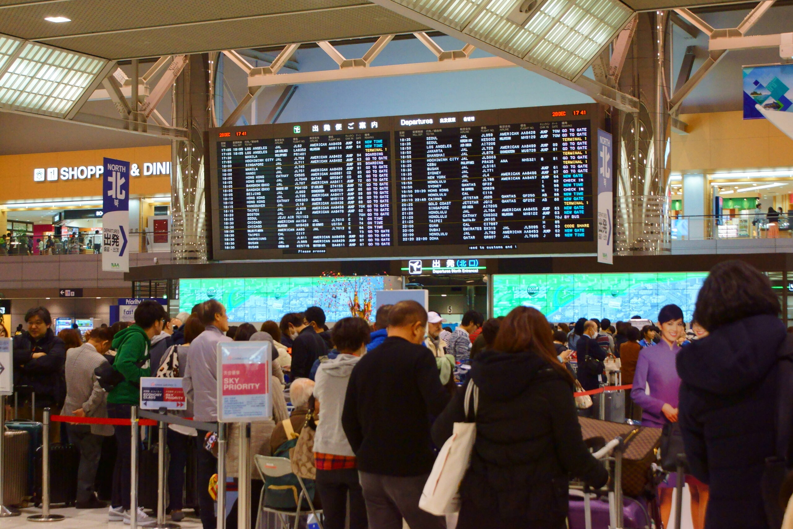 Travelers waiting beneath departure boards at Narita Airport
