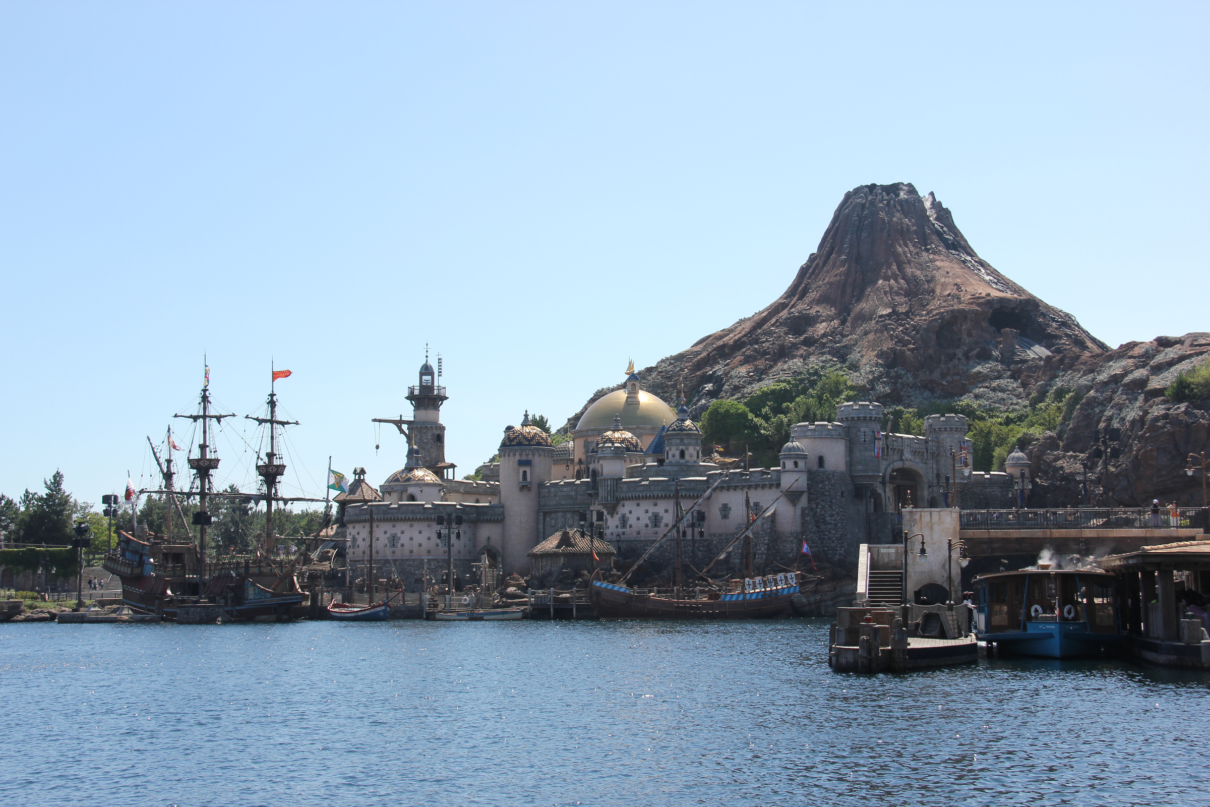 Mount Prometheus, fortress buildings and sailing ships viewed across Mediterranean Harbor at Tokyo DisneySea.