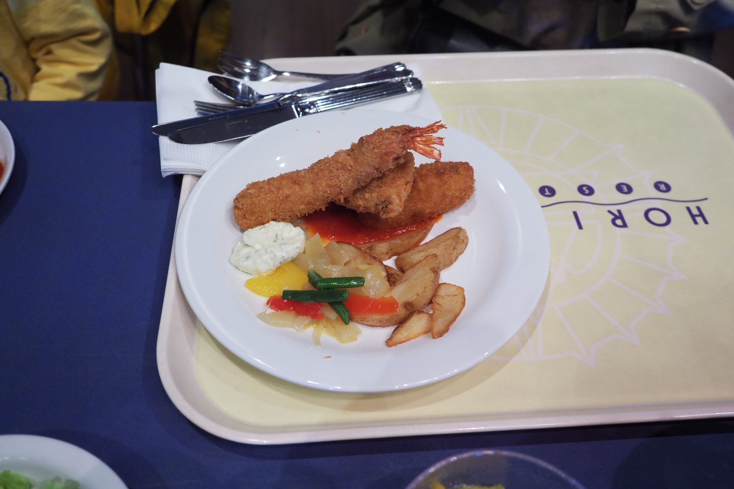 A restaurant plate with breaded shrimp, potato wedges, vegetables and sauce at Tokyo DisneySea.