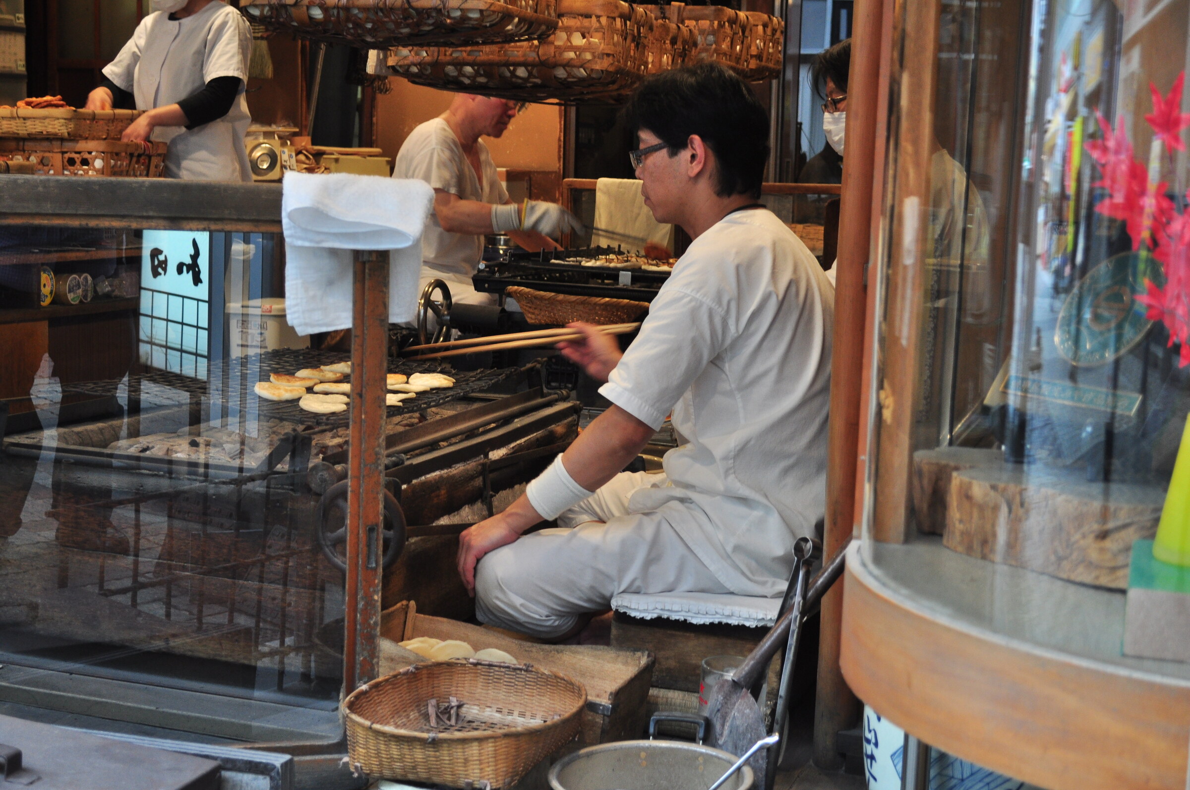 Worker grilling round rice crackers by hand at an Asakusa shop
