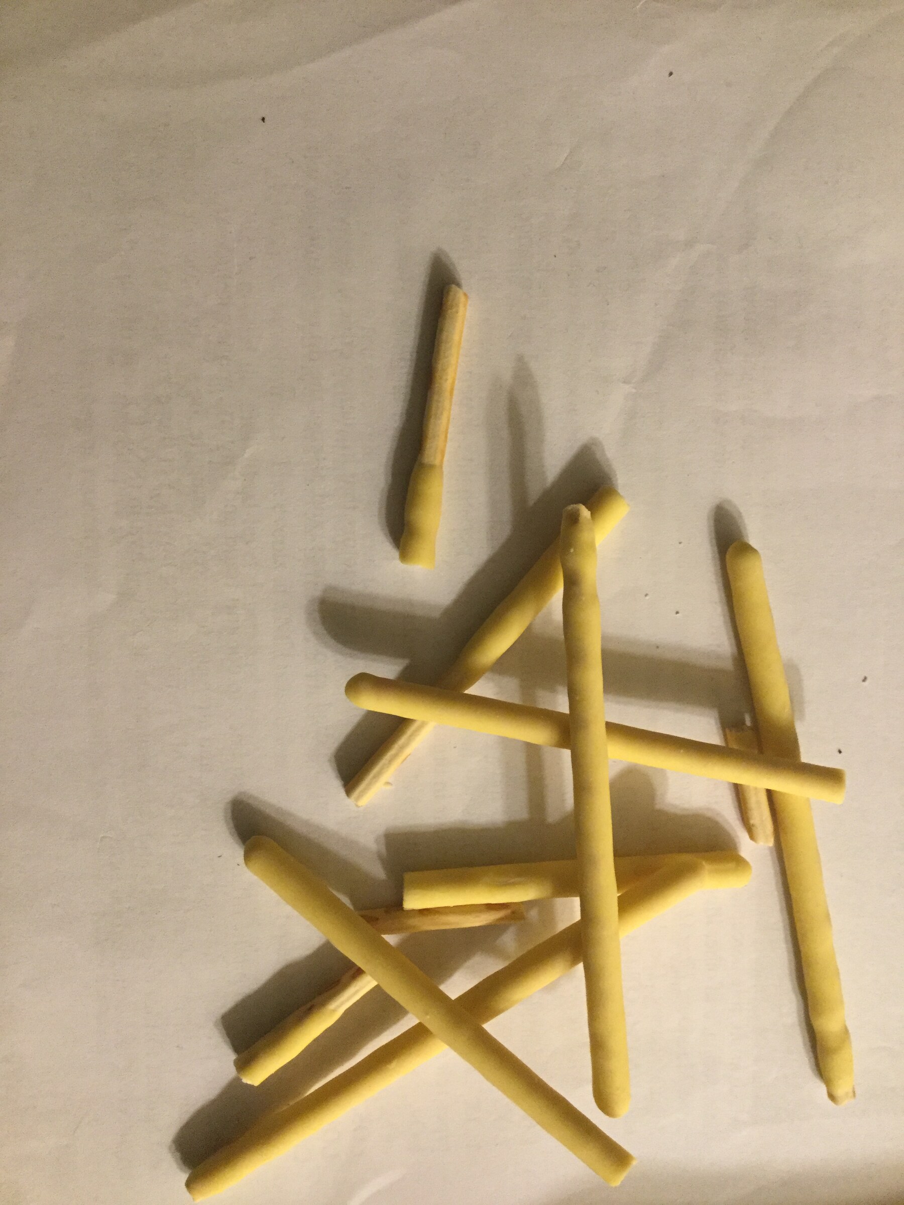 Mango-coated biscuit sticks arranged on a plain surface