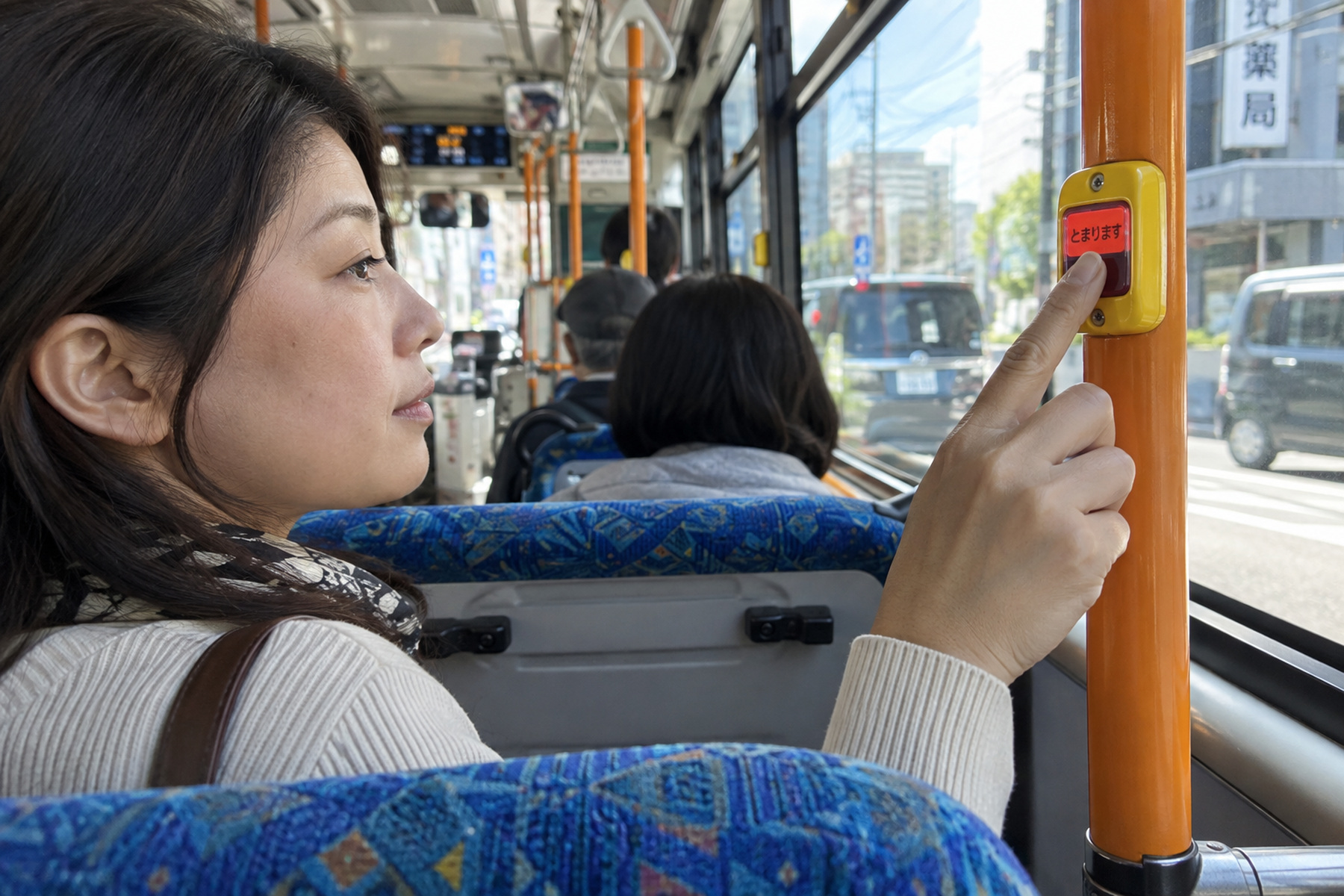 Front of a city bus at a Tokyo bus stop with passengers queued beside the entrance