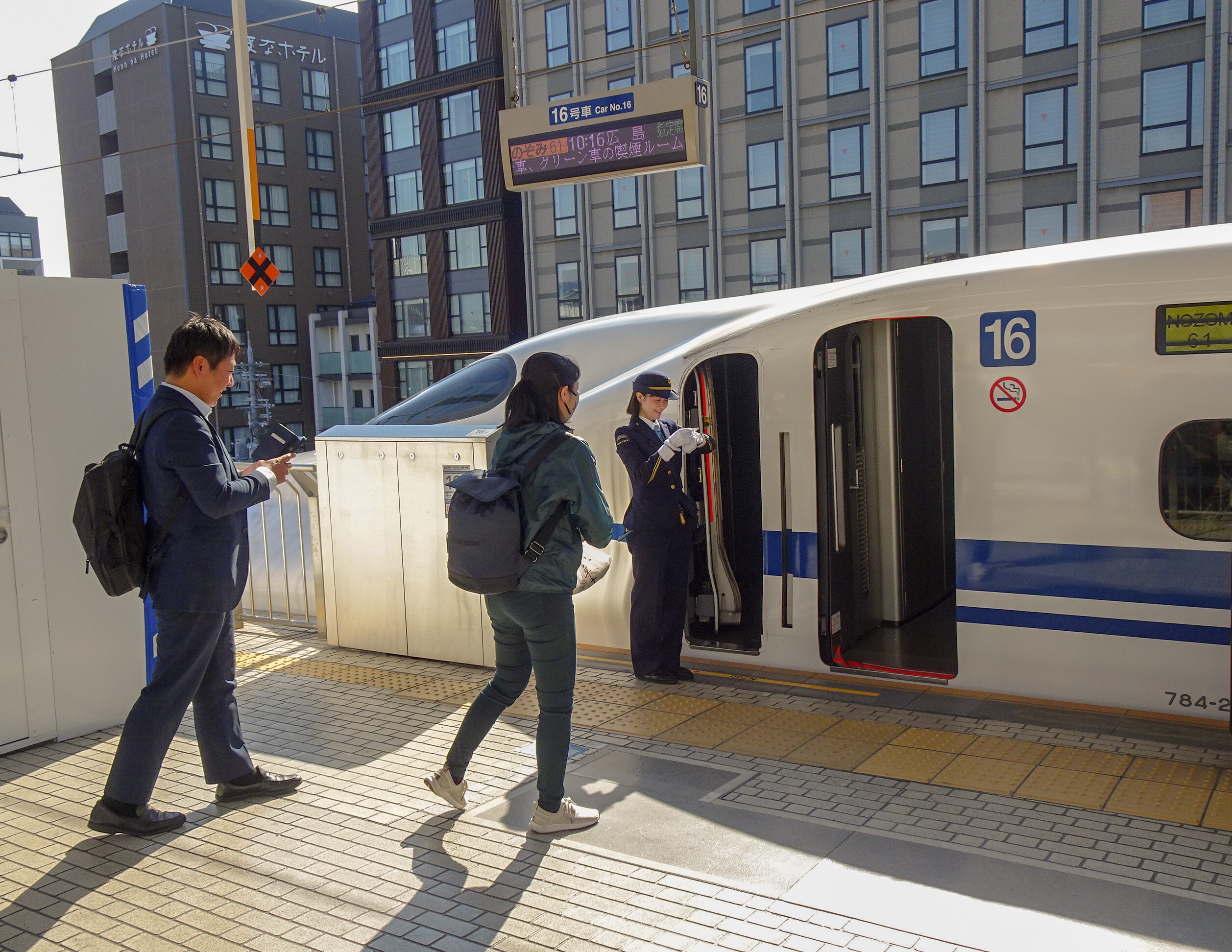 Passengers walking toward an open Shinkansen door on a station platform