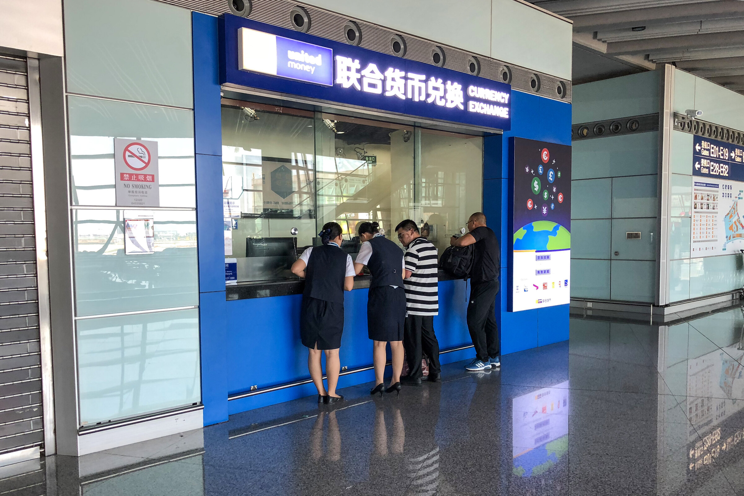 Travelers using a staffed airport currency exchange counter