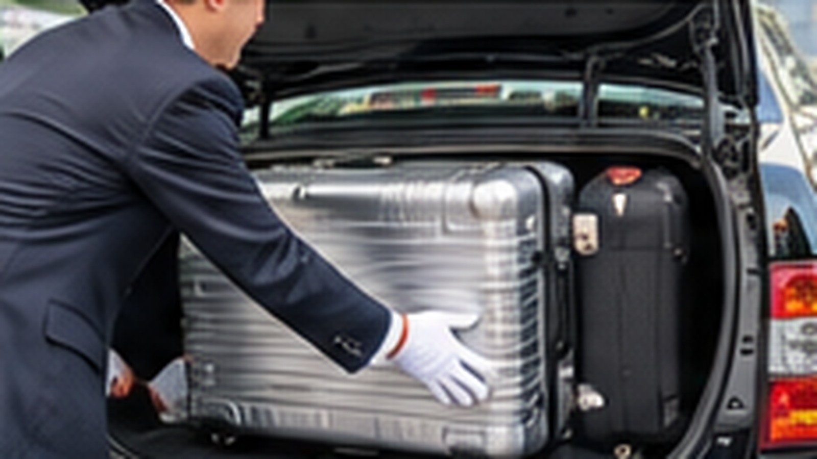 Taxi driver loading large suitcases into a taxi