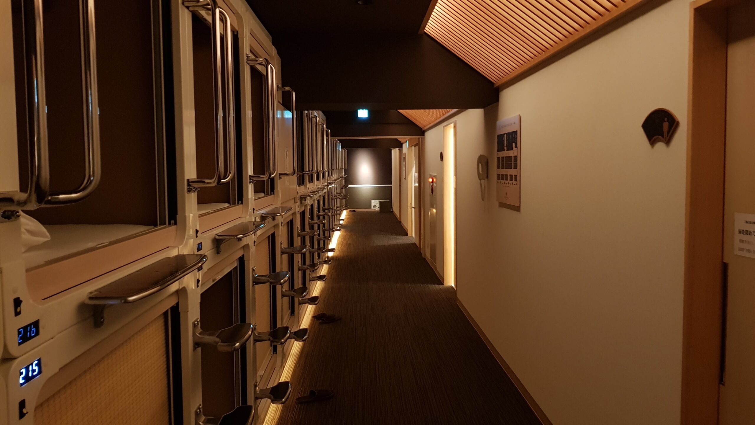 Rows of sleeping pods along a capsule hotel corridor in Japan