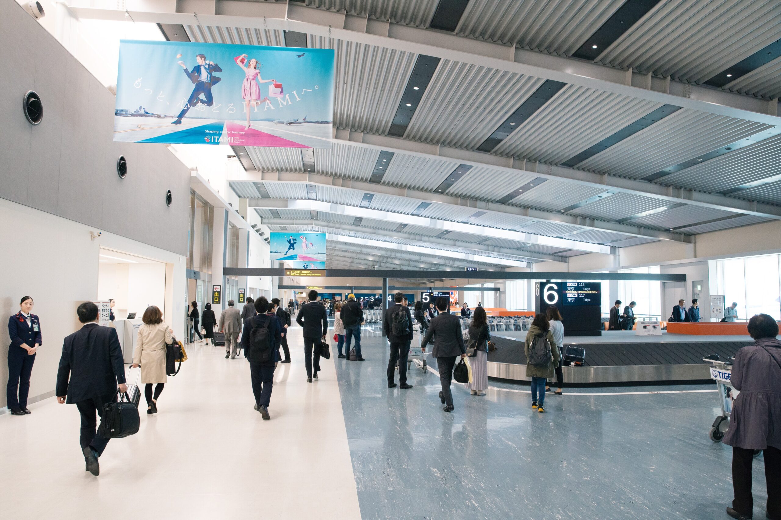 Travelers waiting beside baggage carousels at Itami Airport