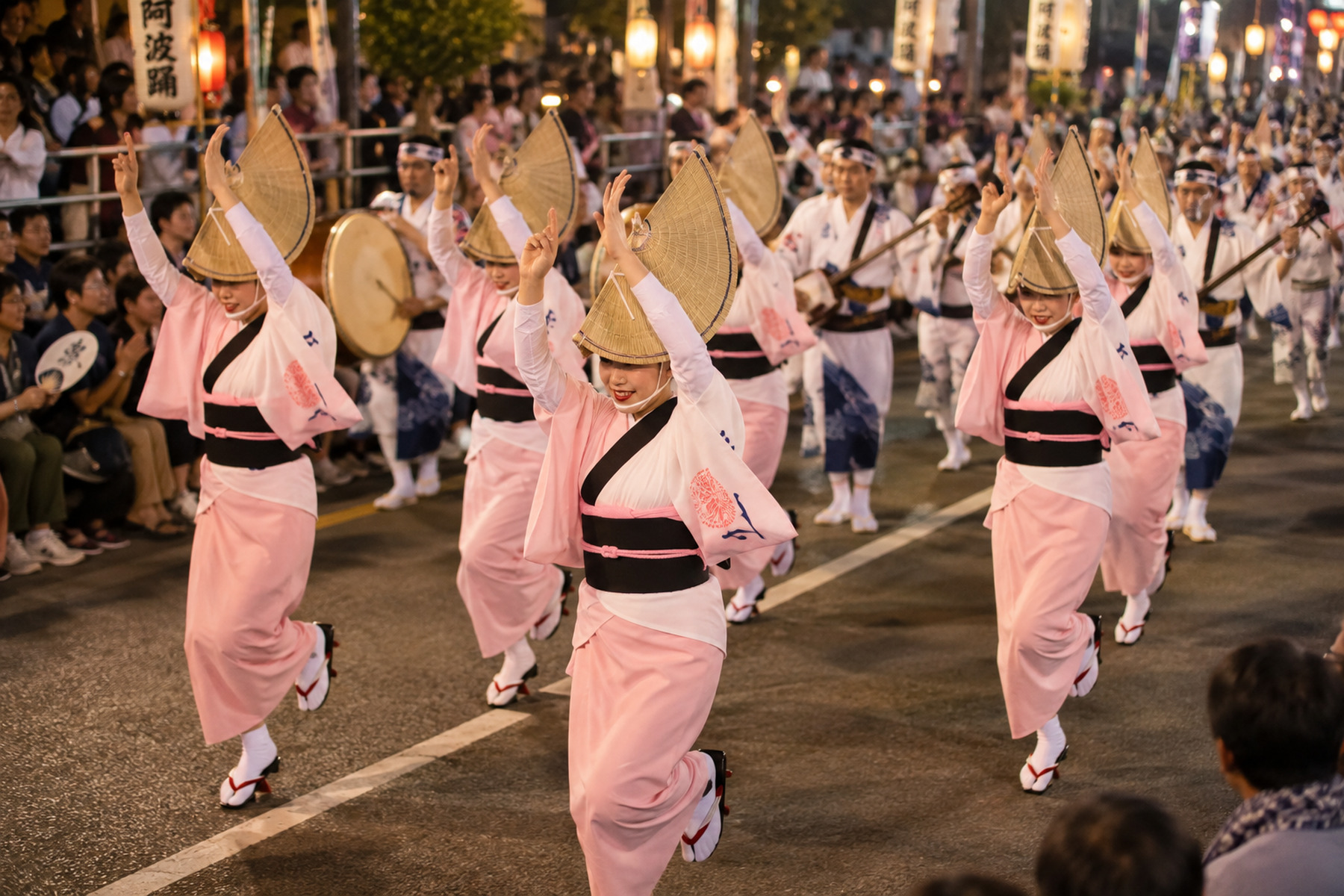Awa Odori-style dancers in straw hats performing in formation with musicians at night