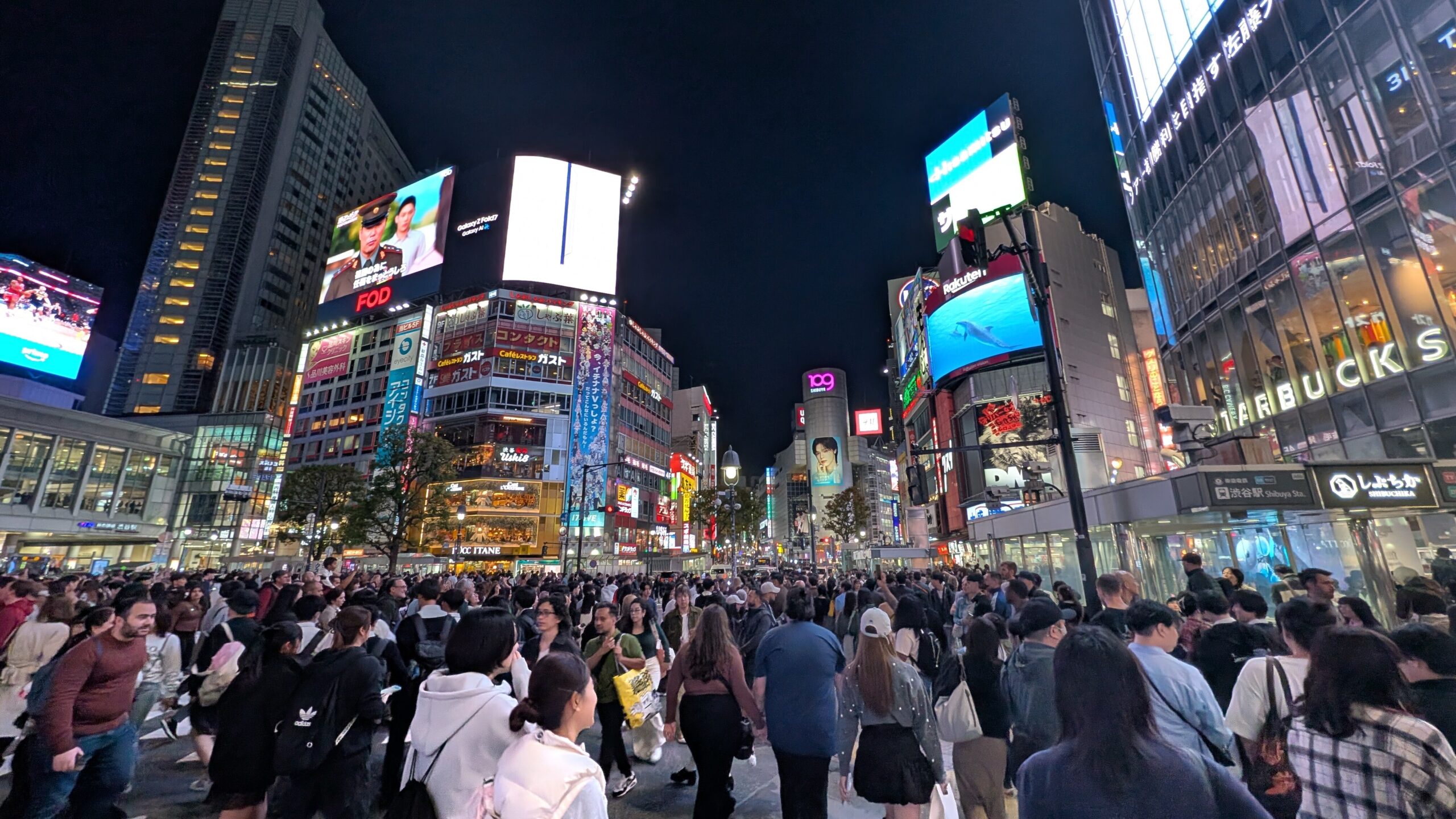 Crowds and illuminated buildings around Shibuya Crossing at night