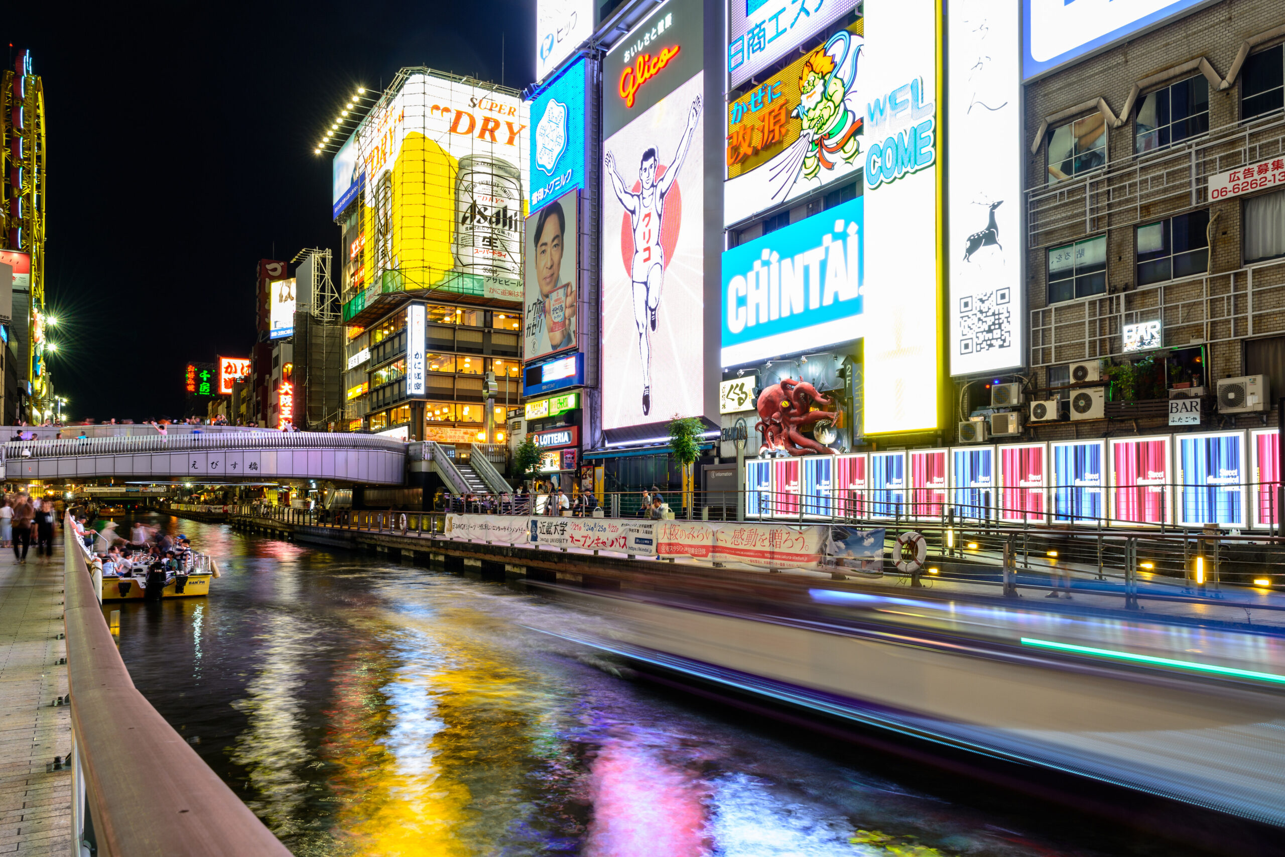 Dotonbori canal, restaurants and illuminated signs at night in Osaka