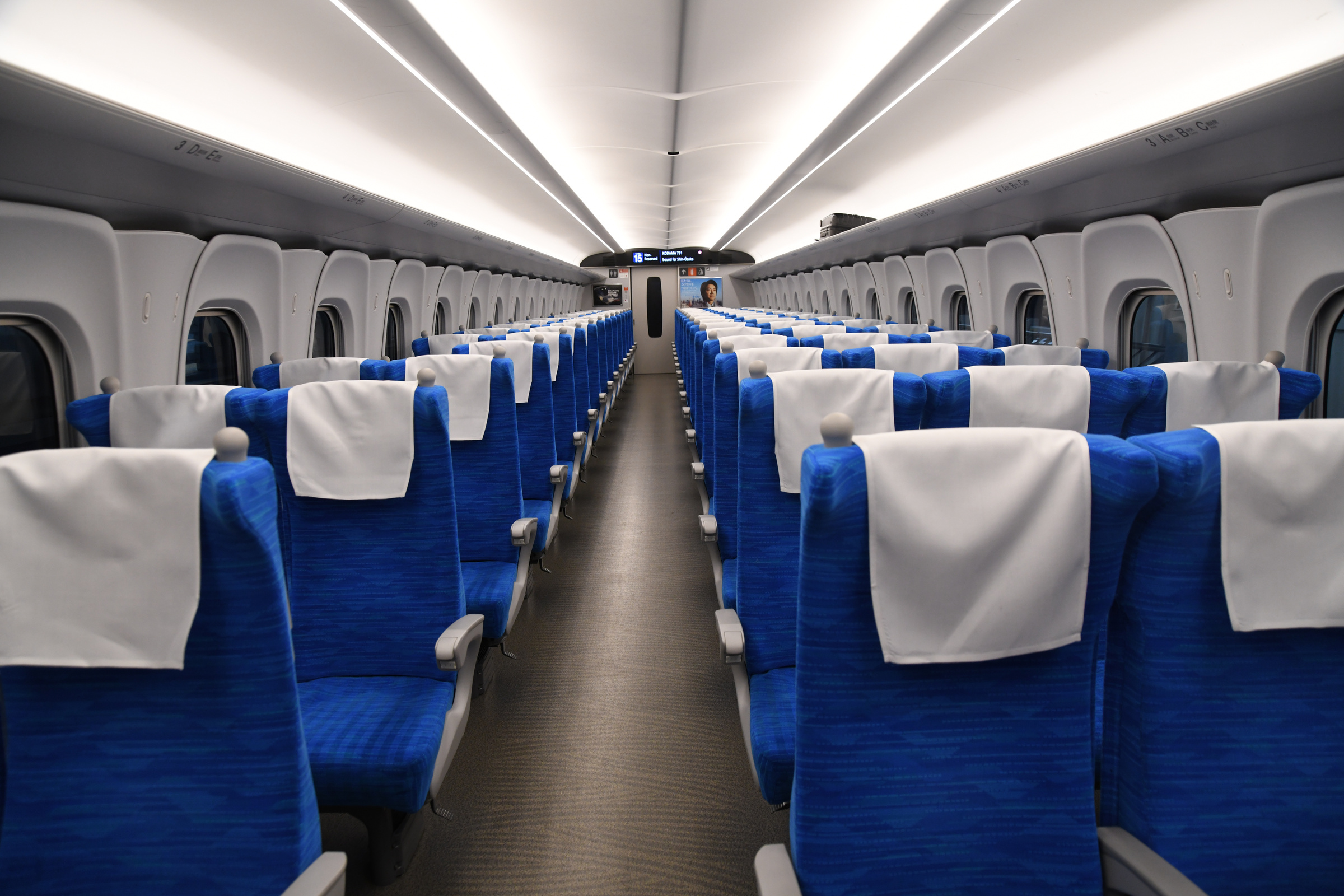 Blue ordinary-class seats and a central aisle inside an N700S Shinkansen.