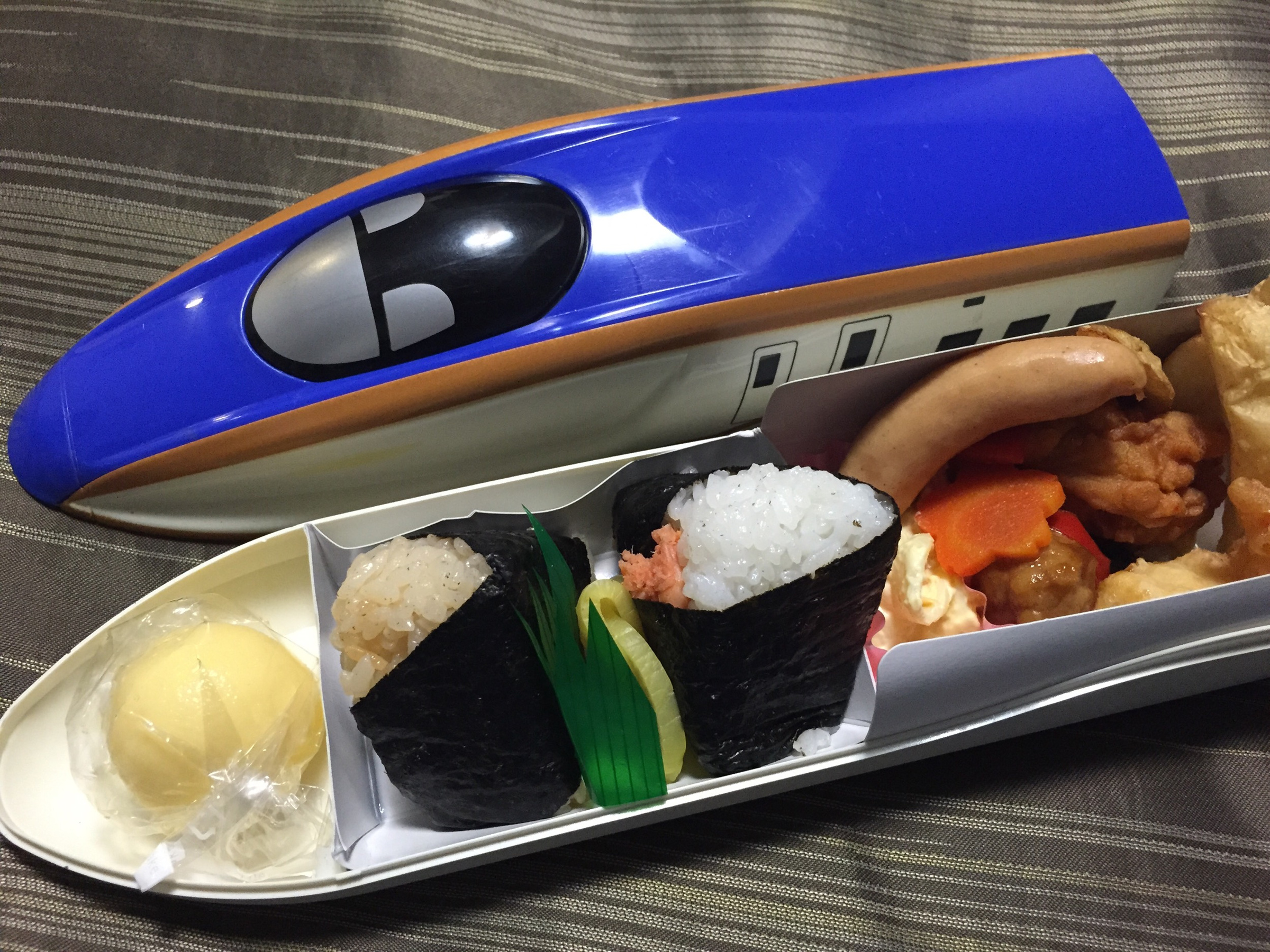 Rice balls and side dishes in an open train-shaped ekiben box.