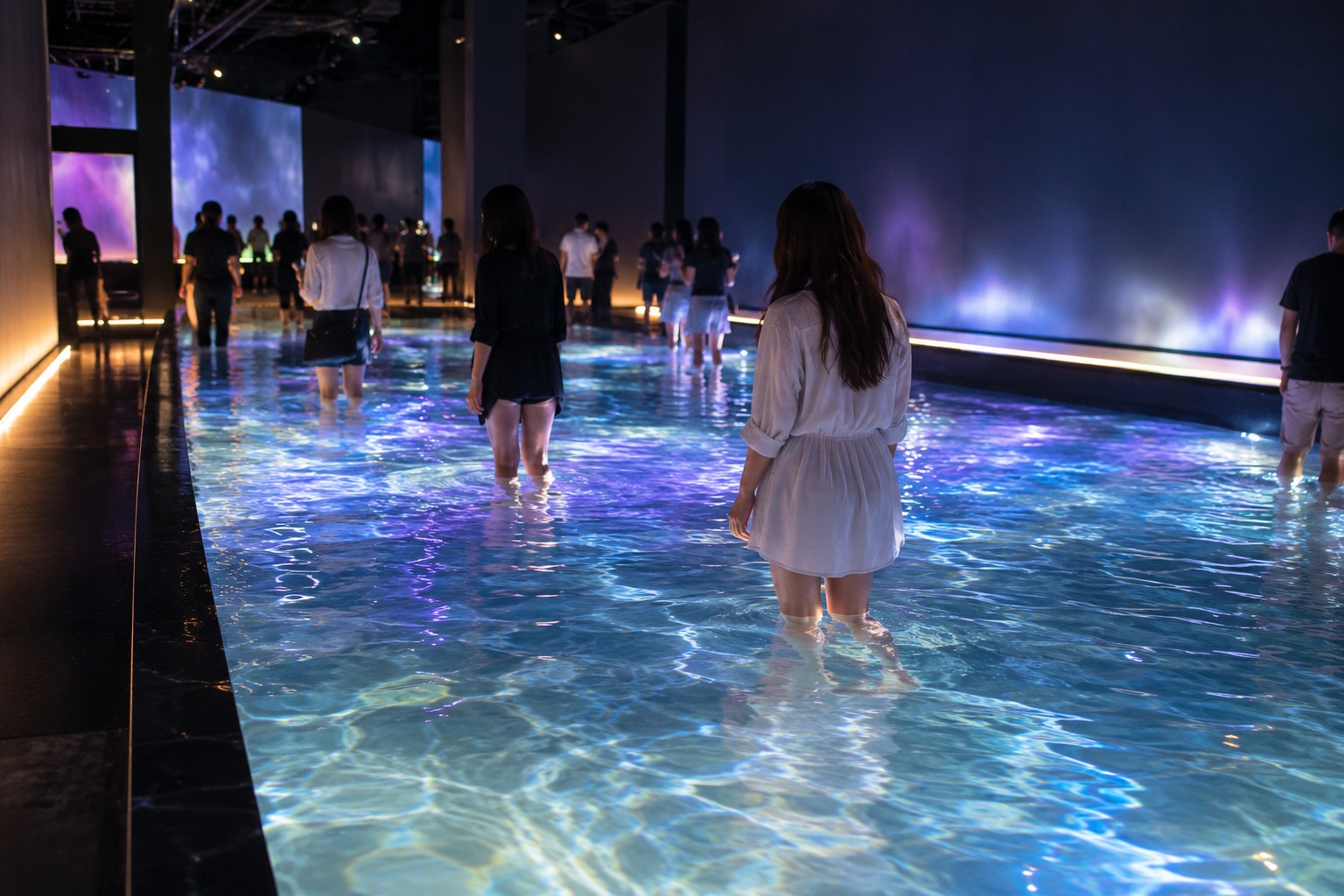 Visitors walking barefoot through a shallow water art installation